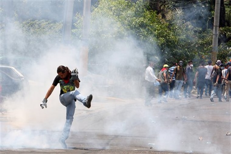 A demonstrator kicks at a cloud of tear gas during a protest in Tegucigalpa, Honduras, on March 24. Teachers have taken to the streets to demand their six months in back pay. The educators are also upset over a bill being discussed by lawmakers that would allow parents to monitor teachers' work in the classroom. At least four soldiers were injured and 13 people arrested Thursday.